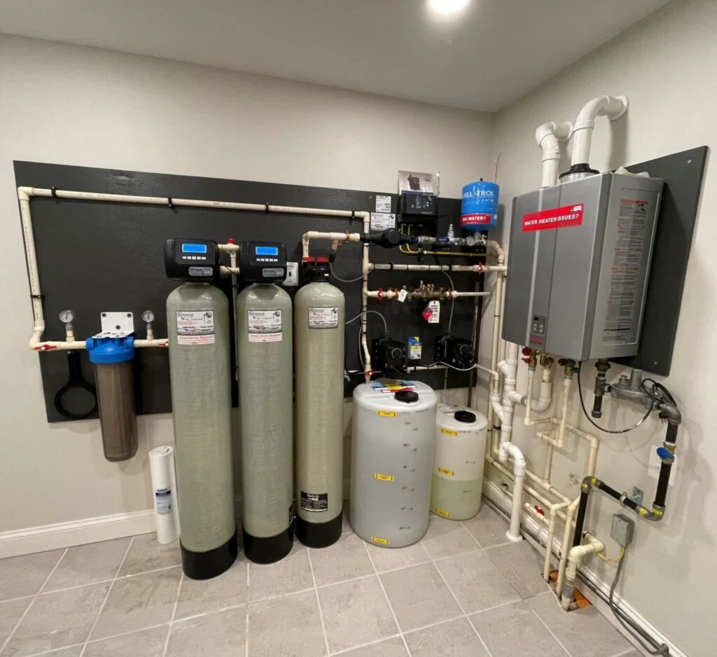 Technician installing whole-home water filtration system beside main water line in Raleigh utility room
